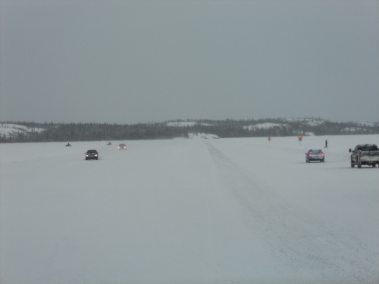 Cars, snowmobiles and people on the ice road